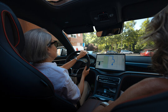 Senior woman driving modern car using navigation system
