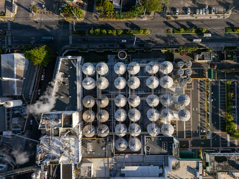 Aerial view of a beer industrial complex with rows of large metallic storage tanks, industrial buildings, and steam rising from vents in Santo Domingo, Dominican Republic.