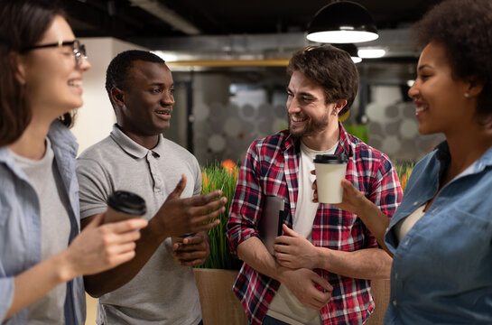 Cheerful diverse colleagues chatting during coffee break in coworking