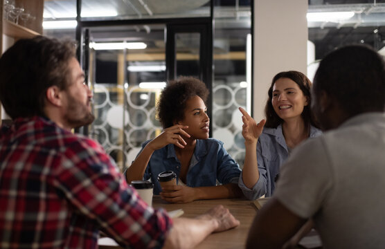 Happy lady speaking with multiethnic colleagues in coworking