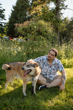 Candid man sitting in park with dog on a sunny summer afternoon