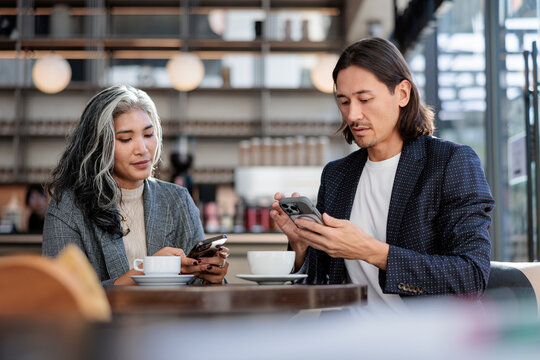 People at cafe using phones with coffee cups