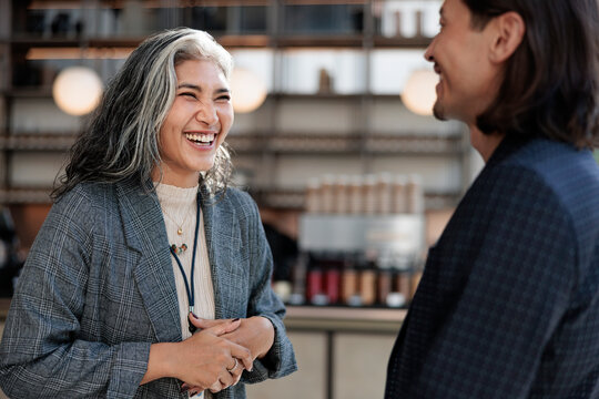 Two people share a joyful moment, laughing together indoors.