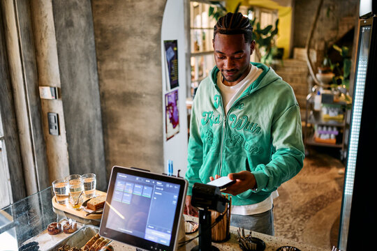 Customer Paying with Smartphone via NFC Terminal at Cafe Counter