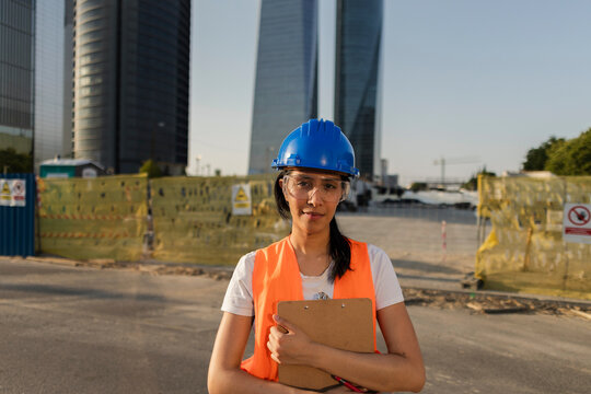 Female construction engineer holding clipboard at urban