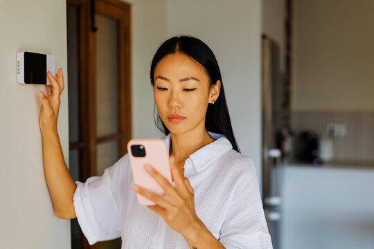 Woman controlling smart home device with smartphone