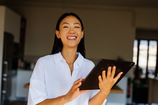 Woman laughing enjoying digital device at home
