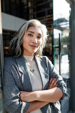 Confident woman with silver hair in a plaid blazer.