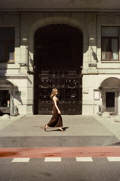 A woman in a dark maxi dress walks past wrought iron gates