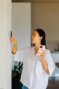 Woman controlling smart home temperature with device and smartphone