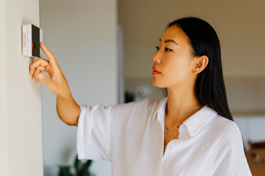 Woman adjusting smart home thermostat for comfort