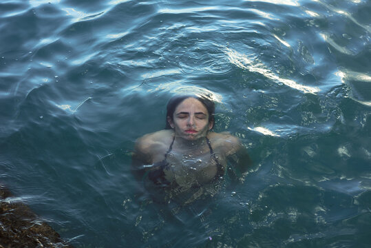 Woman in a bikini emerges from the sea