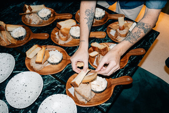 Hands Preparing Bread and Cream on Wooden Plates at a Kitchen Table