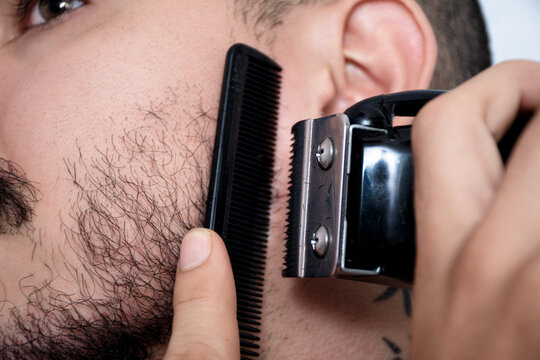 Man Grooming Beard With Comb and Clippers