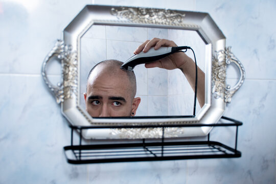 Man Shaving Head in Bathroom With Mirror