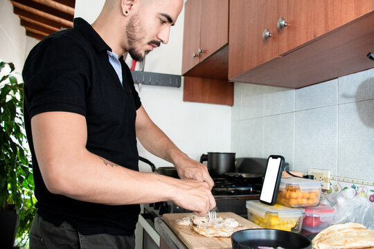 Man Cooking in a Kitchen While watching his phone