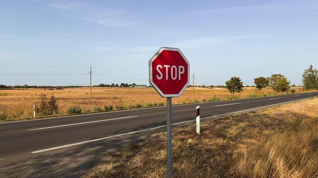 STOP traffic sign prominently standing along an empty rural highway. Concept of road safety, traffic regulation, country driving, and law compliance. 4K.