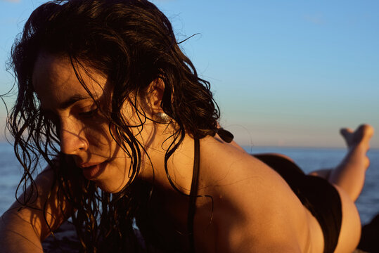 Woman illuminated with warm sunset light while lying on rocks