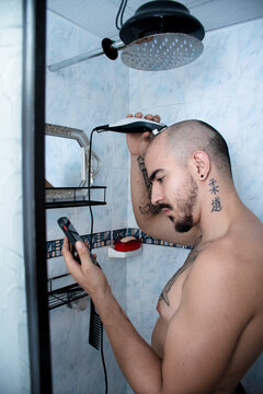 Man Using Trimmer in the Shower While Checking Phone
