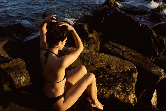 Woman sitting on rocks by the sea