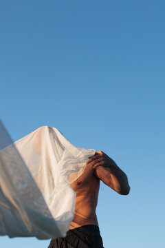A Topless Man Wraps Himself In A Soft Transparent Cloth Outdoors