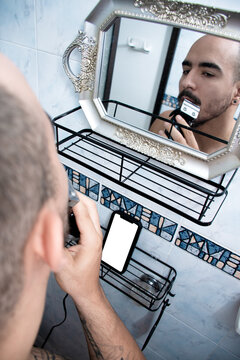 Man Shaving in Bathroom While Looking in the Mirror