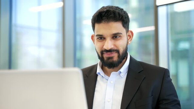Happy satisfied businessman received great news on laptop while sitting at workplace in business office. Joyful smiling male worker in formal suit reads positive good message on computer. Close up.