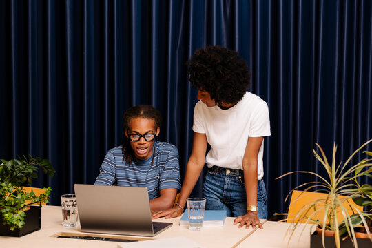 Two diverse entrepreneurs working together at a shared desk.