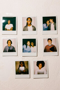 Instant photos of a diverse young team taped to a rough white wall.