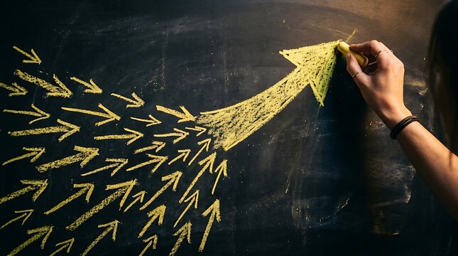 A person drawing many small yellow chalk arrows converging into one big arrow on a chalkboard