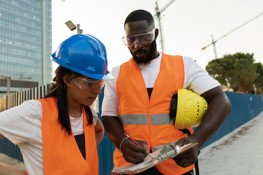 Construction workers reviewing building plans at site