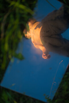 Reflection of Male body Person in Mirror Surface On Grass