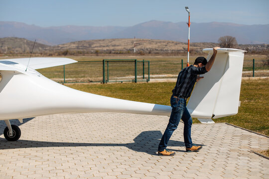 Pilot Pushing Glider Tail at Rural Airfield