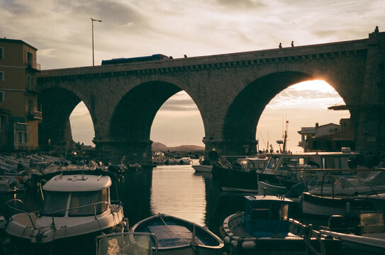 Stone arch bridge over a harbour at sunset