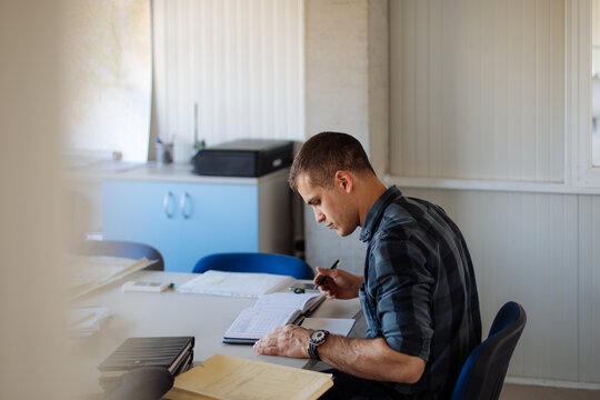 Man Working at Desk With Documents and Maps