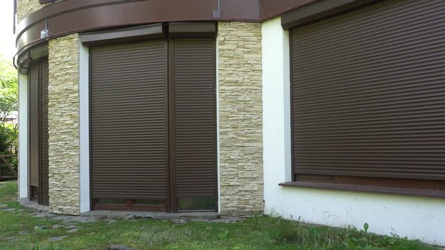The shutters are raised on the windows of the house. The facade of a modern building with brown shutters on the windows.