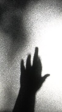 A shadow of a hand showing the middle finger. An obscene shadow of the gesture on a wall. Concept of anger and protest.