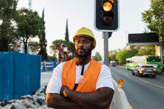 Confident black construction worker standing at urban site