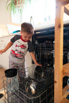 Young boy helping load dishwasher in bright family kitchen