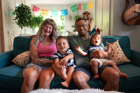 Candid family portrait of parents and two young children on couch