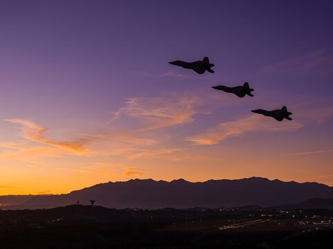 Three military fighter jets fly in formation above a mountainous landscape