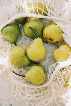 Cream mesh shopping bag with pears and dappled sunlight