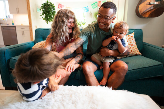 Candid family moment with parents and children laughing on couch