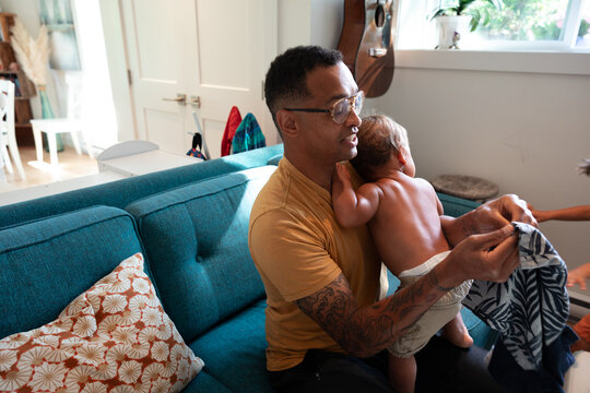 Candid father holding toddler at home, caring family moment
