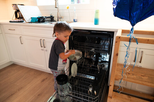Young boy loading dishwasher in kitchen helping with chores