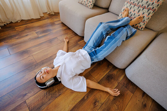 Woman relaxing on floor listening music with headphones