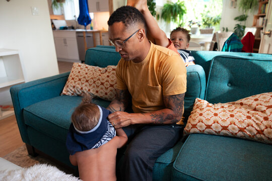 EDITOR'S NOTE: NOT IN FOCUS, HAS SOME MOTION Candid father playing with kids on couch at home, real family life