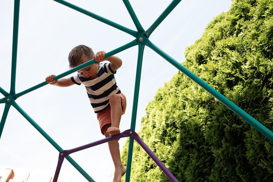 Candid boy climbing playground jungle gym outdoors on a sunny day
