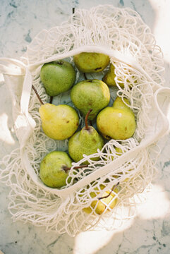 Cream mesh shopping bag with pears and dappled sunlight