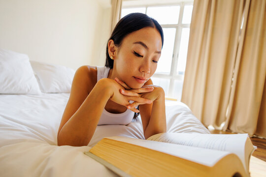 Woman relaxing on bed reading a book